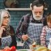 Grandparents and granddaughter preparing salad in home kitchen, creating memories together.