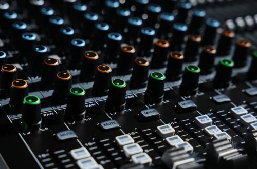 Detailed view of an audio mixing console with colorful lights in a professional studio setting.
