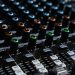 Detailed view of an audio mixing console with colorful lights in a professional studio setting.